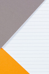 Geometric background with gray and orange colored paper and blank lined paper page. Top view, copy...