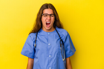 Young nurse woman isolated on yellow background  screaming very angry and aggressive.