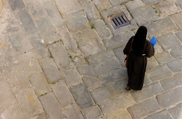 one nun walking along the old cobblestones 