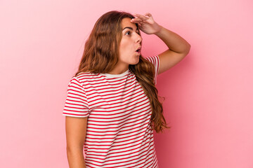Young caucasian woman isolated on pink background  looking far away keeping hand on forehead.