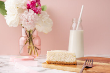 Homemade cheesecake and milk . French dessert and flowers on marble table on pink background