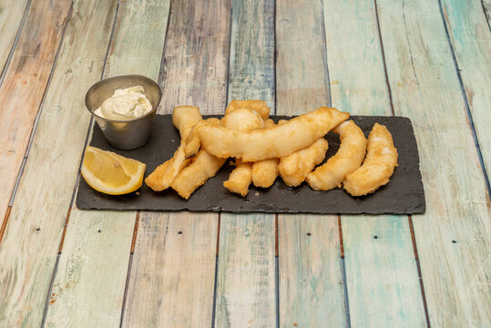 Great and fat squid squid battered and fried in olive oil with lemon and mayonnaise to garnish in a Spanish tapas restaurant