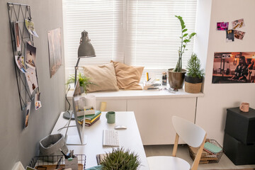 Part of room with workplace of modern freelancer by wall and other things