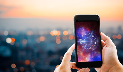 Astrological zodiac horoscope Mobile application concept.Man hands holding mobile phone on blurred...