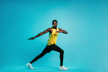 Fototapeta na wymiar Young sportsman standing on blue background. Athlete warming up his body during a workout.