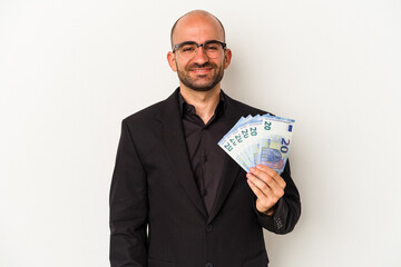 Young business bald man holding bills isolated on white background  happy, smiling and cheerful.