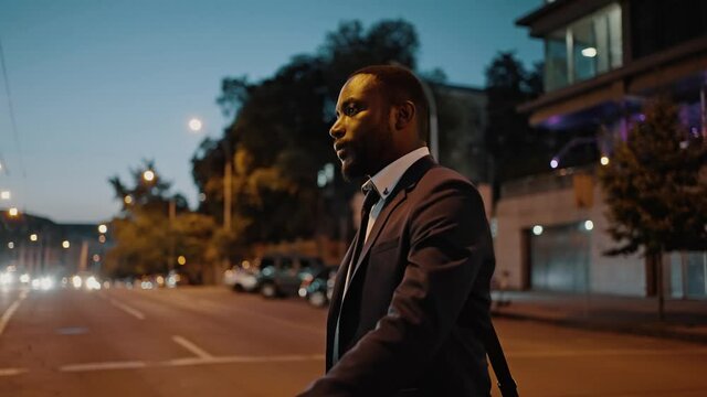 Night activity. Serious african american businessman wearing suit overpassing urban road, going home in big city