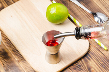 Making a red cocktail with lime and ice.