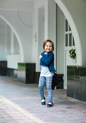 a beautiful little girl, a schoolgirl, in the afternoon near the school, in a school uniform