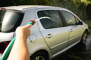 Fototapeta premium Man cleaning a car with a hose