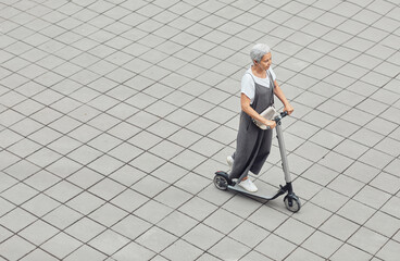 Graphic high angle view at contemporary mature woman riding electric scooter in city across tiled background, copy space