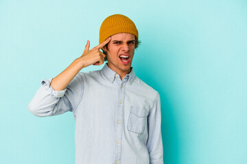 Young caucasian man with make up isolated on blue background  covering ears with hands.