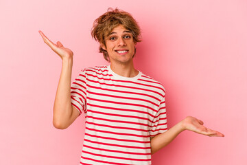 Young caucasian man with make up isolated on pink background confused and doubtful shrugging...