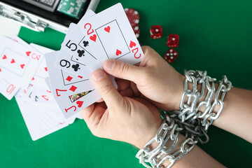 Men hands are tied with chain and hold playing cards closeup