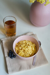 yellow flakes in a pink plate with blueberries and juice