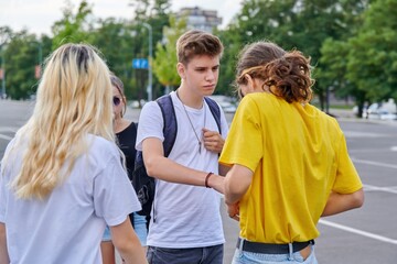 Group of teenagers in city, serious guy talking to friend