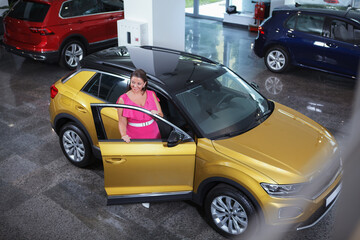 Top view shot of a cheerful female buying new car at the dealership