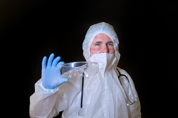 Medic in covid protective suit with mask and glasses scars on his face, black background