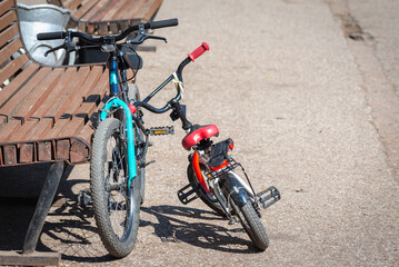 Naklejka na ściany i meble Small and large children's bike by the park bench.