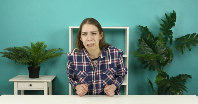 Sad brunette woman shows disgust to the camera. A young girl waves her arms.