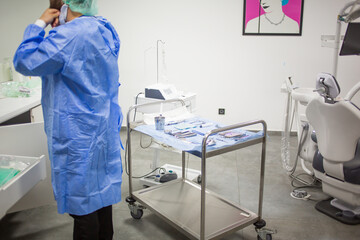 A dentist is preparing for a dental surgery in his medical office. Dental chair, equipment and tools on a background