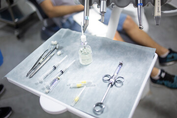 Medical tray table with dental tools, medicines and equipment, patient in a dental chair on a background.