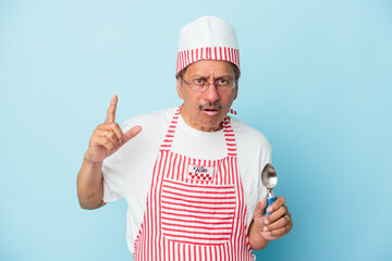 Senior indian ice cream man holding a scoop isolated on blue background having an idea, inspiration concept.