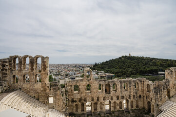 Remains of The Odeon of Herodes Atticus in Athens. Cityscape of Athens at cloudy day. Acropolis hill.