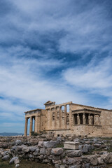 Remains of ancient marble temple on Acropolis hill in Athens, Greece. The Erechtheion, ancient Greek settlement. Cloudy sky. Nobody. Landmark of Athens.
