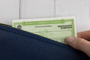 Removing the Brazilian voter's title from the wallet. Womans hand holding the Brazilian voter title - obrazy, fototapety, plakaty