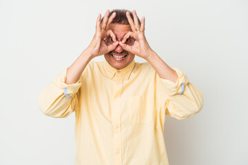 Middle aged indian man isolated on white background excited keeping ok gesture on eye.