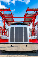 Red big rig semi truck with two level modular car hauler semi trailer waiting for the next load...