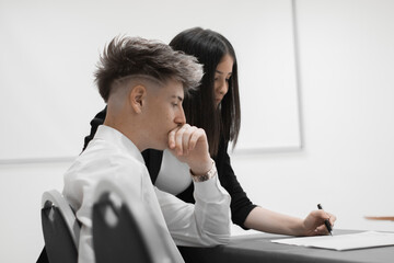 Chica joven en una conferencia de trabajo explicando informes de trabajo junto a un muchacho 