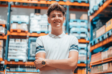 Hombre joven encargado en un almacen revisando las estanterias del comercio con una sonrisa