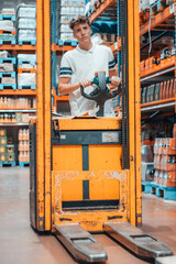 Chico joven trabajador en un almacen revisando las normas de seguridad con las maquinas y carretillas elevadoras