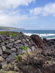 Vertical landscape of peaceful beach in shore with rocks and ocean with waves in island of são miguel, açores, azores, portugal