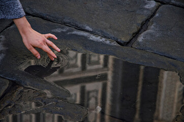 Atmospheric photo of a girl's hand touching the reflection of the cathedral in the water, Florence