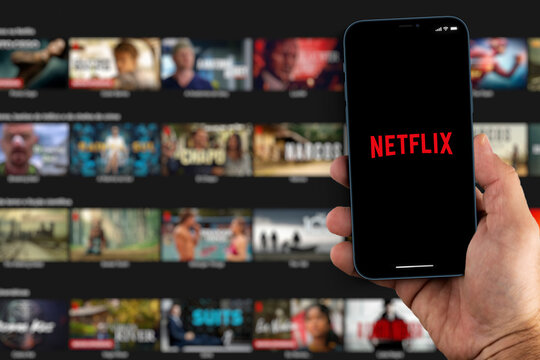 Male hand holding a smartphone with Netflix App on the screen with de website blurred on background. Rio de Janeiro, RJ, Brazil. August 2021.