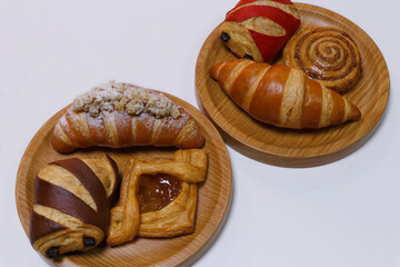 Assorted French pastry cake- Danish roll, scone, muffin and croissant displayed in a wooden board