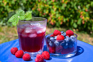 Summer appetizer. Blackberries and raspberries on blue plate and a glass with berry juice