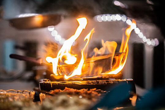 Copper pan engulfed in flames on cooking burner at outdoor resort buffet