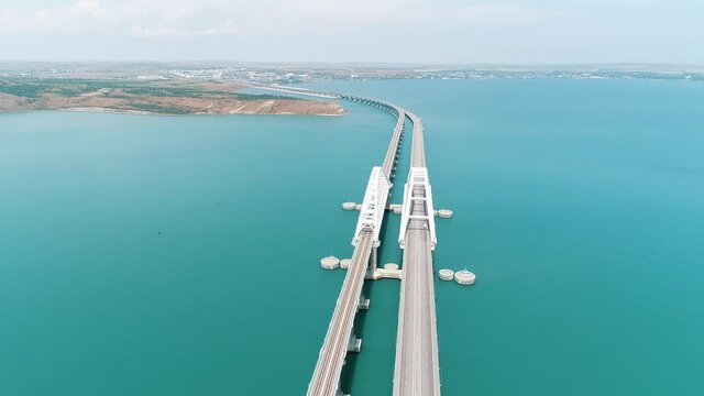Aerial view of the crimean Bridge across the Kerch Strait. Shot. Amazing long bending bridge above calm turquoise sea.