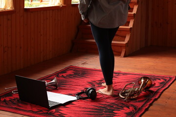 Female feet barefoot with a laptop white sheet of paper on the keyboard with musical instrument...