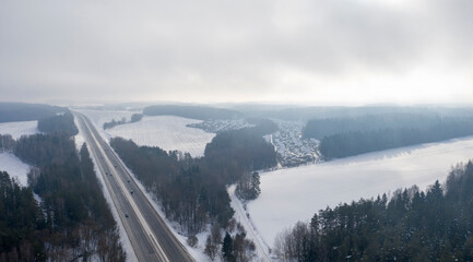 Aerial bird-eye view on freeway road in the winter forest.