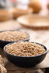 Wheat grain in a black bowl on wooden background