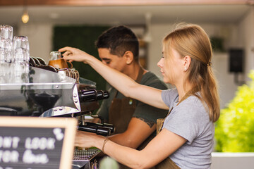 Fototapeta na wymiar A mid age woman barista making coffee in a machine