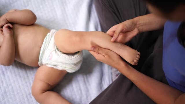 Woman massages the leg of a lying smiling child