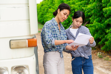 Young and Adult Asian women speaking near truck