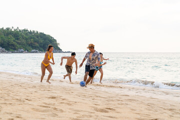 Group of Happy Asian man and woman friends playing beach soccer together on tropical beach in sunny...