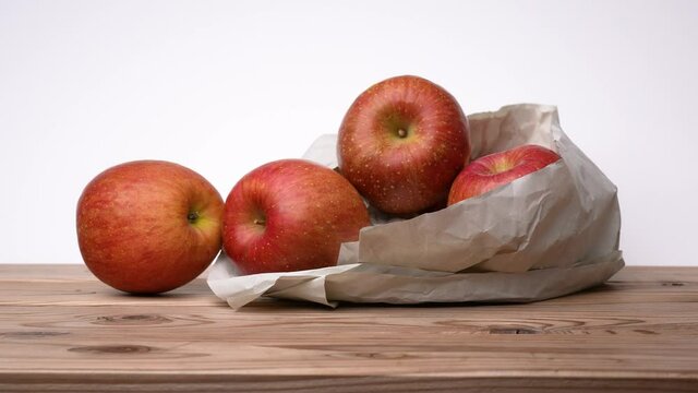 Red apple on board with white background, shot from the side, Dolly video.